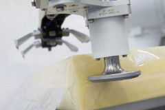 Met een robot wordt de folie om de kaas opengesneden