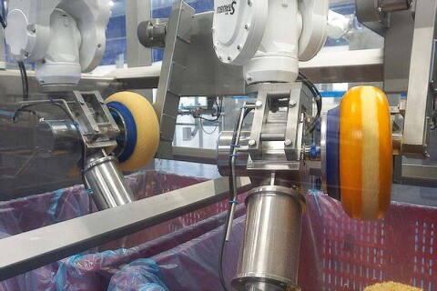 Met behulp van 2 robots wordt de korst van ronde kazen verwijderd